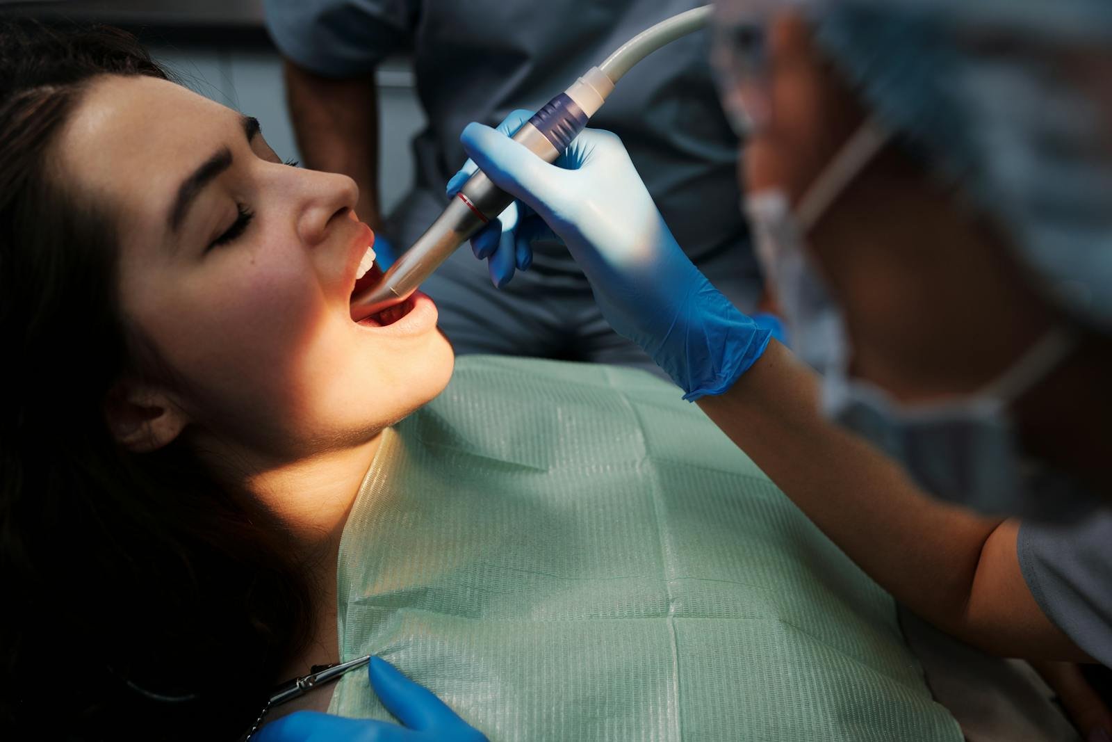 Close-up of a woman receiving dental treatment with modern equipment at a clinic.